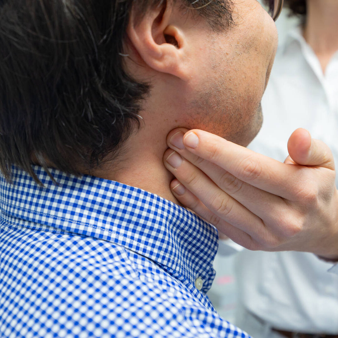 Nahaufnahme eines männlichen Patienten welcher den Hals von Dr. Carola Hummel abgetastet bekommt