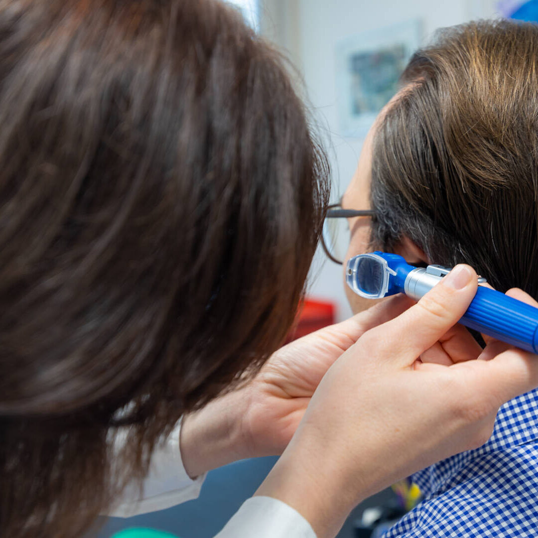 Nahaufnahme Untersuch am Ohr eines männlichen Patienten durch Dr. Carola Hummel